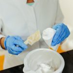 Técnica de laboratório usando luvas mistura um creme para cuidados com a pele durante um procedimento de pesquisa.