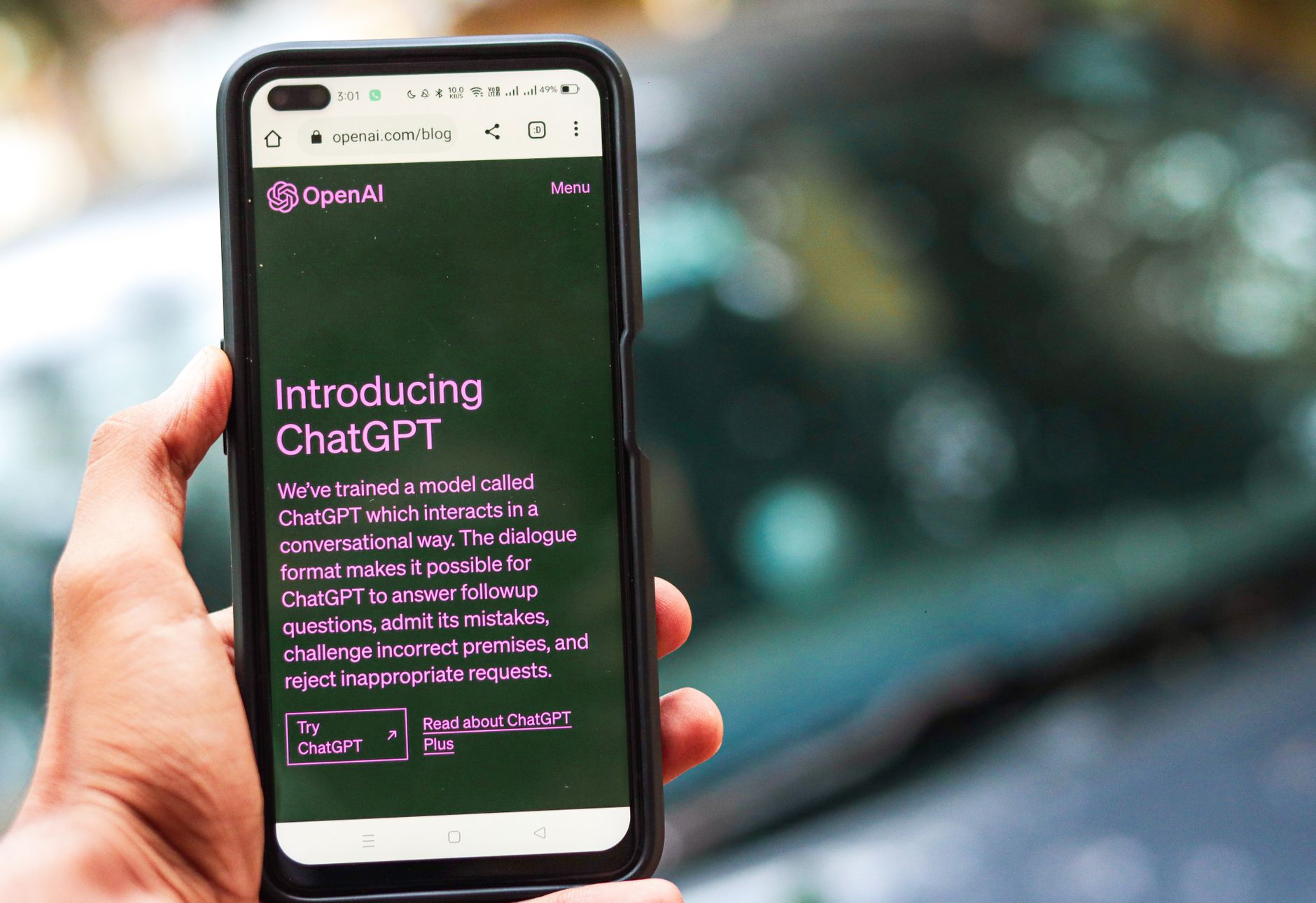 Pessoa segura um smartphone que exibe a interface do ChatGPT em uma página da OpenAI.