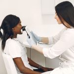 Profissional realiza análise da pele do rosto de uma paciente com equipamento em uma clínica.