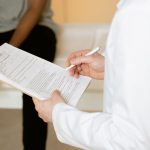 Profissional de saúde analisa um formulário durante consulta em uma clínica.