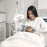 Profissional realiza um tratamento facial estético em uma cliente em uma clínica moderna.