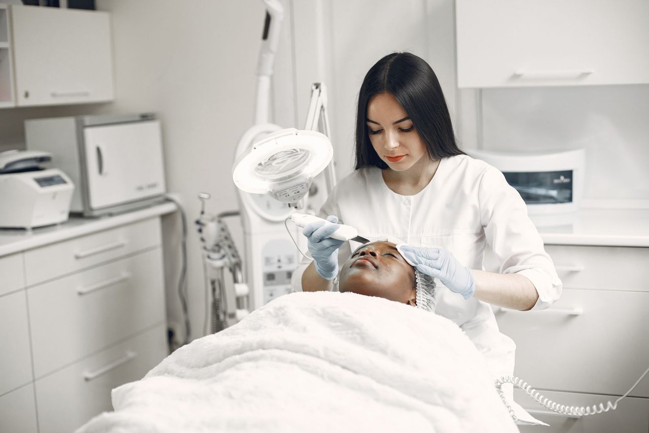 Profissional realiza um tratamento facial estético em uma cliente em uma clínica moderna.