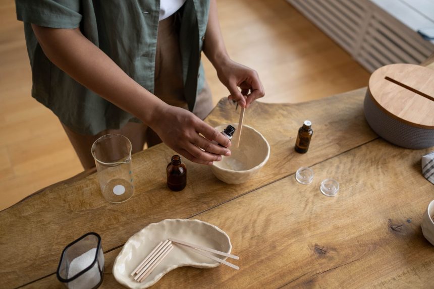 Mãos preparando artesanalmente um bálsamo labial em um ambiente interno de produção.