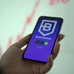 Mão segurando um smartphone com a tela de uma carteira digital de criptomoedas baseada em blockchain.