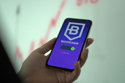 Mão segurando um smartphone com a tela de uma carteira digital de criptomoedas baseada em blockchain.