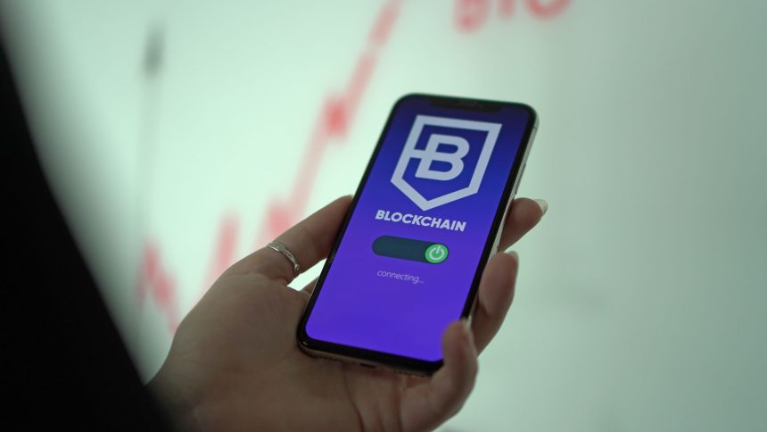 Mão segurando um smartphone com a tela de uma carteira digital de criptomoedas baseada em blockchain.
